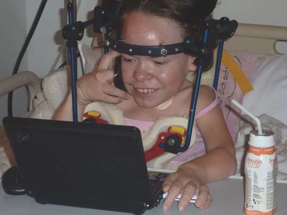Maria nach der Wirbelsäulen-OP 2010 mit Laptop | MPS Austria Mädchen mit MPS Typ 4 nach der Wirbelsäulen-OP mit Laptop